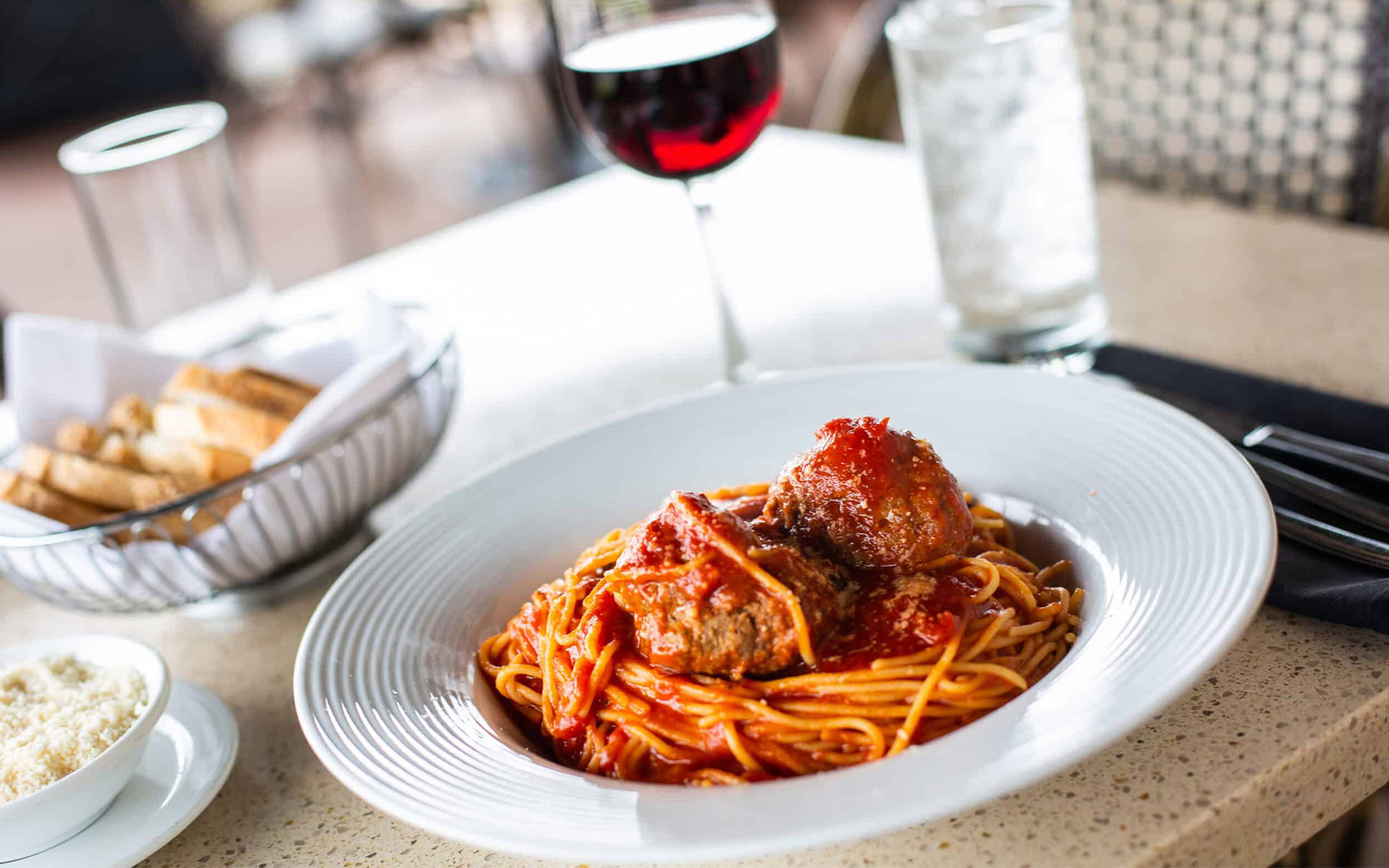 Spaghetti And Meatballs Next To Wine And Bread
